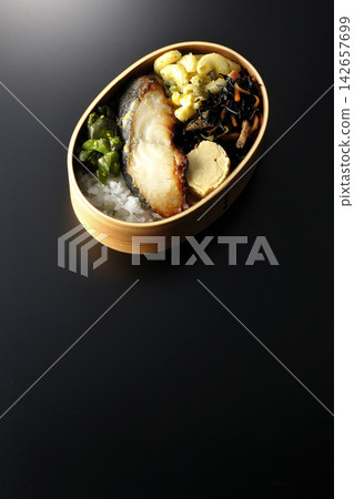 A bento box of grilled silver cod marinated in Saikyo miso, photographed against a black background. A bento box of grilled silver cod marinated in Saikyo miso, photographed against a black background. 142657699