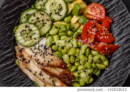 An Asian style bowl with eel, edamame, avocado, tomatoes, and lettuce. A eel and vegetable bowl An Asian style bowl with eel, edamame, avocado, tomatoes, and lettuce. A eel and vegetable bowl 142658015