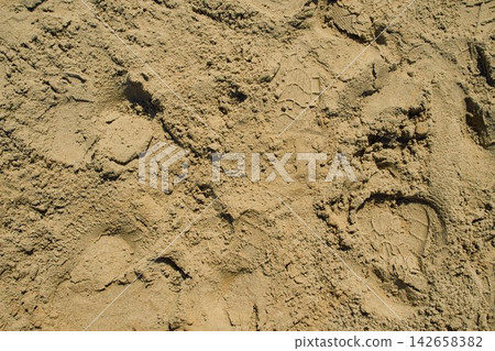 An abstract texture of yellow-brown construction aggregate sand with a shoe sole indentation An abstract texture of yellow-brown construction aggregate sand with a shoe sole indentation 142658382