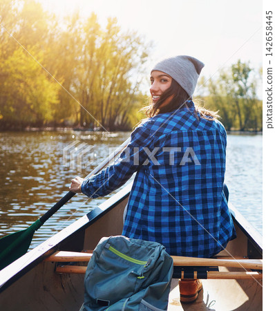 Nature, lake and portrait of woman canoeing for adventure on summer vacation, getaway or weekend trip. Water sports, boat and female person with paddle for kayaking on holiday with outdoor hobby. Nature, lake and portrait of woman canoeing for adventure on summer vacation, getaway or weekend trip. Water sports, boat and female person with paddle for kayaking on holiday with outdoor hobby. 142658445