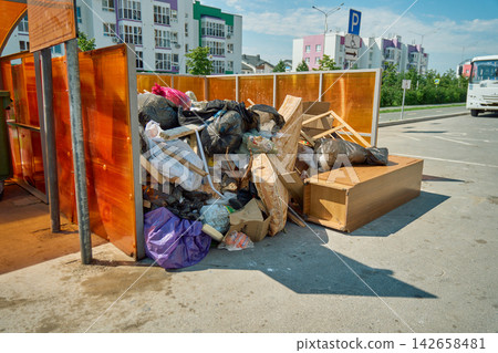 Spring mattress leaning against overfilled plastic trash bags at an unofficial waste collection site in a residential area Spring mattress leaning against overfilled plastic trash bags at an unofficial waste collection site in a residential area 142658481