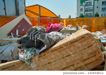 Massive Accumulation of Unwanted Bulky Household Goods and Waste Cluttering Street Pavement Near Metal Outdoor Dumpsters Massive Accumulation of Unwanted Bulky Household Goods and Waste Cluttering Street Pavement Near Metal Outdoor Dumpsters 142658612