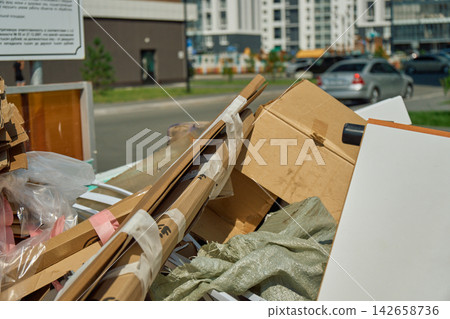 Detailed view of tied bundles of discarded cardboard packaging boxes and paper materials piled up for waste disposal at an urban collection area Detailed view of tied bundles of discarded cardboard packaging boxes and paper materials piled up for waste disposal at an urban collection area 142658736