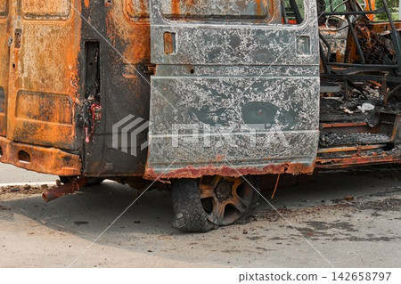 Side view of a completely burnt out, rusty and destroyed transport van left on a city parking lot Side view of a completely burnt out, rusty and destroyed transport van left on a city parking lot 142658797