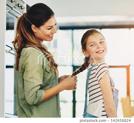 Braiding, child and mom with skills, laughing and grooming with smile, home and woman with daughter. Family, mother and hairstyle change for girl in kitchen, bonding and hair maintenance with routine 142658824
