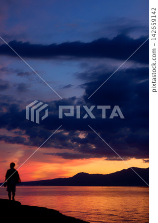 Evening view of the Osabeta Seashore Road | The setting sun sinking into the Ariake Sea and a man walking alone Evening view of the Osabeta Seashore Road | The setting sun sinking into the Ariake Sea and a man walking alone 142659142