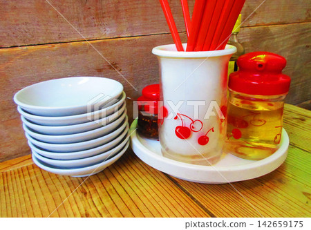餐廳餐桌上擺放著一套調味品(餐桌調味品)。 餐廳餐桌上擺放著一套調味品(餐桌調味品)。 142659175
