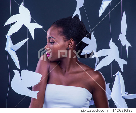 Art, beauty and bird origami with black woman in studio on gray background for makeup. Cosmetics, paper and skincare with confident and creative model on backdrop for hygiene, natural or wellness Art, beauty and bird origami with black woman in studio on gray background for makeup. Cosmetics, paper and skincare with confident and creative model on backdrop for hygiene, natural or wellness 142659383