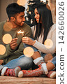 Couple, people and happy in home with sparklers for Christmas, festive and holiday celebration. Relationship, love and smile for bonding with firework in winter for joy, fun and tradition as soulmate 142660026