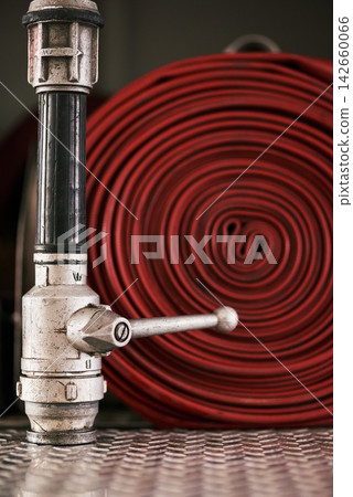 Emergency, equipment and pipe with red fire hose for security, danger or health and safety at station. Closeup of gear, tool or pressure extingusher ready in rescue, service or firefighting operation Emergency, equipment and pipe with red fire hose for security, danger or health and safety at station. Closeup of gear, tool or pressure extingusher ready in rescue, service or firefighting operation 142660066
