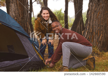Woods, camping and portrait of couple with tent in outdoor countryside in Norway for adventure date. Interracial people, love and travel with shelter for wilderness on holiday or vacation in nature. Woods, camping and portrait of couple with tent in outdoor countryside in Norway for adventure date. Interracial people, love and travel with shelter for wilderness on holiday or vacation in nature. 142660590
