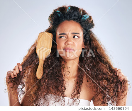 Beauty, knots and woman with brush in hair on studio gray background for haircare frustration. Annoyed, face or moody and unhappy African model in bathroom with morning routine or haircare problems 142660594
