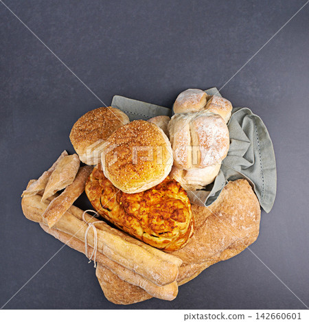 Group, bread and roll by dark background for bakery, sandwich and Italian food on surface with carbs. Bun, baguette and gluten free with wheat on countertop for healthy eating, hamburger and focaccia Group, bread and roll by dark background for bakery, sandwich and Italian food on surface with carbs. Bun, baguette and gluten free with wheat on countertop for healthy eating, hamburger and focaccia 142660601