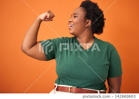 Black woman, power and smile in orange background with arm flex for leader, gender equality and confident. Happy, proud and fist of girl for success, tough and strength in studio for empowerment Black woman, power and smile in orange background with arm flex for leader, gender equality and confident. Happy, proud and fist of girl for success, tough and strength in studio for empowerment 142660603
