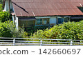 Dilapidated vacant house and guardrails overgrown with weeds; aging wooden house; vacant house problem; social problem 142660697