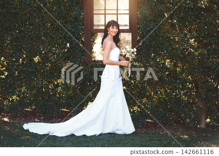 Happy woman, portrait and wedding dress with bouquet of flowers in nature for marriage, ceremony or commitment. Married, young female person with fashion or style in floral, lush or natural greenery Happy woman, portrait and wedding dress with bouquet of flowers in nature for marriage, ceremony or commitment. Married, young female person with fashion or style in floral, lush or natural greenery 142661116