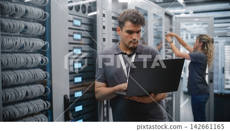 Male IT Engineer Monitoring Server Performance in Modern Data Center Male IT Engineer Monitoring Server Performance in Modern Data Center 142661165