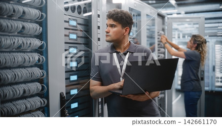 Male IT Engineer Monitoring Server Performance in Modern Data Center Male IT Engineer Monitoring Server Performance in Modern Data Center 142661170