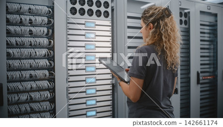 Female Data Center Technician Monitoring Server Rack Status With Tablet And LED Displays Female Data Center Technician Monitoring Server Rack Status With Tablet And LED Displays 142661174