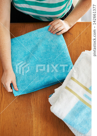 Laundry, folding and hands in home with towel, clothes and fresh linen on table with housekeeper in apartment. Cleaning service, cloth and washing fabric for hygiene, safety and comfort in house Laundry, folding and hands in home with towel, clothes and fresh linen on table with housekeeper in apartment. Cleaning service, cloth and washing fabric for hygiene, safety and comfort in house 142661377