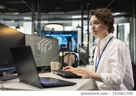 Programmer at office desk using machine learning programming languages displayed on PC screen. Worker using computer in AI company workspace to run deep learning algorithms simulations 142661380