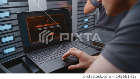 Male Cybersecurity Engineer Analyzing Critical Cyber Attack Warning in Data Center Male Cybersecurity Engineer Analyzing Critical Cyber Attack Warning in Data Center 142661412