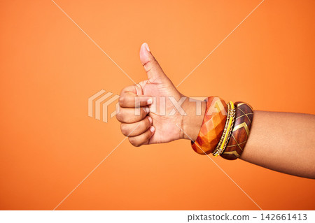 Hand, thumbs up and person with arm on orange background for thank you or confirm with gesture or sign. Good news, expression and positive with yes or thanks with win in studio for agreement. Hand, thumbs up and person with arm on orange background for thank you or confirm with gesture or sign. Good news, expression and positive with yes or thanks with win in studio for agreement. 142661413