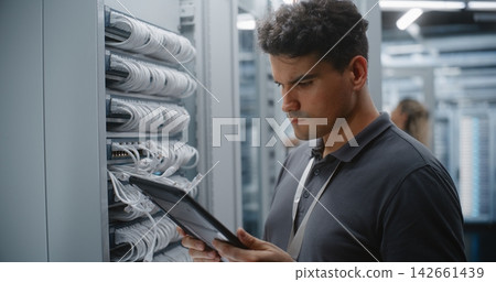 Male Network Technician Verifying Patch Panel Connections with Tablet Reference Male Network Technician Verifying Patch Panel Connections with Tablet Reference 142661439