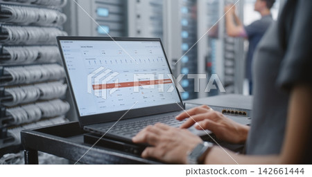 Female Engineer Responding to Critical Server Overheating Alert in Data Center Female Engineer Responding to Critical Server Overheating Alert in Data Center 142661444