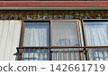 A dilapidated house with a torn screen door, rusty exterior walls, and old windows. 142661719