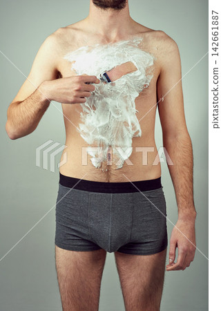 Shaving body, man and grooming in studio for skin care, hair removal and daily routine on gray background. Male person, razor and foam on chest for hygiene, epilation and cleaning for wellness Shaving body, man and grooming in studio for skin care, hair removal and daily routine on gray background. Male person, razor and foam on chest for hygiene, epilation and cleaning for wellness 142661887