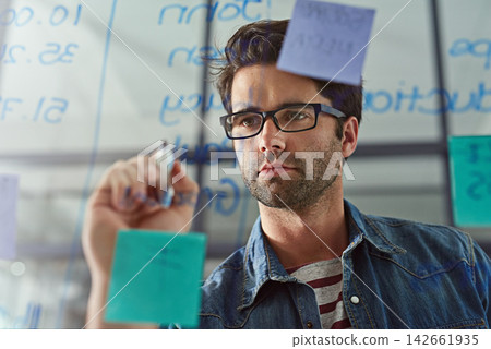 Face, glass and planning with business man writing in office to brainstorm company strategy. Mindmap, mission and schedule with confident young employee in workplace for strategy on storyboard Face, glass and planning with business man writing in office to brainstorm company strategy. Mindmap, mission and schedule with confident young employee in workplace for strategy on storyboard 142661935