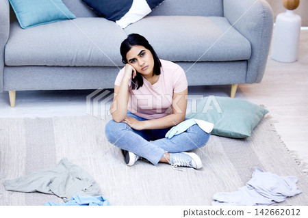 Woman, clothes and portrait on messy floor with tired, house work and laundry in apartment. Frustrated female cleaner, burnout and fatigue in living room for cleaning chaos with stress and overworked 142662012