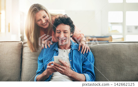 Mature, couple and happy on sofa with phone for reading online news, social media scroll and embrace in home. People, hug and laughing with smartphone for funny meme, bingo or digital gaming on couch Mature, couple and happy on sofa with phone for reading online news, social media scroll and embrace in home. People, hug and laughing with smartphone for funny meme, bingo or digital gaming on couch 142662125