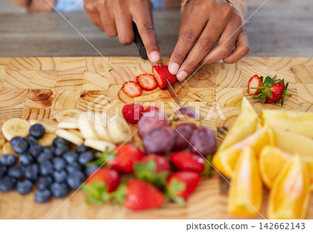 Hands, fruit and cutting on board in kitchen, nutrition and fresh or raw food for detox in home. Fingers of person, knife and chopping organic ingredients for vegan diet, vitamins and minerals Hands, fruit and cutting on board in kitchen, nutrition and fresh or raw food for detox in home. Fingers of person, knife and chopping organic ingredients for vegan diet, vitamins and minerals 142662143