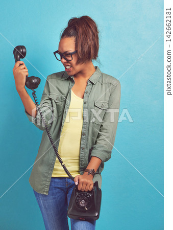 Telephone, angry and screaming with woman, stress and frustrated on blue studio background. Person, furious and girl with communication, rude or upset with emotion, reaction and aggressive with model Telephone, angry and screaming with woman, stress and frustrated on blue studio background. Person, furious and girl with communication, rude or upset with emotion, reaction and aggressive with model 142662181