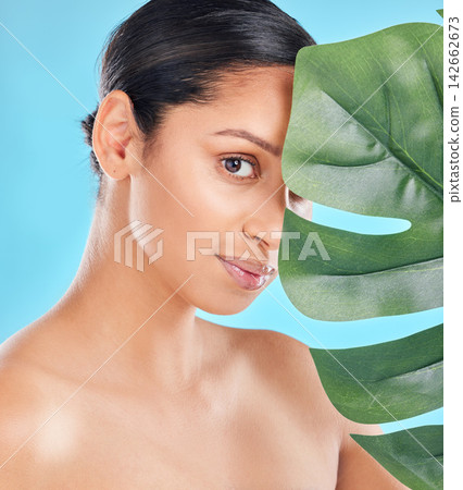 Woman, beauty and palm leaf with skincare glow from spa treatment and natural cosmetics. Model, skin and face of person relax after dermatology detox in a studio with blue background feeling healthy Woman, beauty and palm leaf with skincare glow from spa treatment and natural cosmetics. Model, skin and face of person relax after dermatology detox in a studio with blue background feeling healthy 142662673