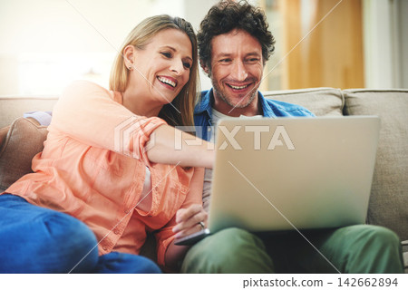 Couple, sofa and laptop in home, relax and point for choice with movie, show or streaming subscription. Mature people, man and woman with computer on couch in living room with talking, film and smile Couple, sofa and laptop in home, relax and point for choice with movie, show or streaming subscription. Mature people, man and woman with computer on couch in living room with talking, film and smile 142662894