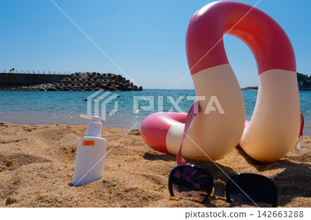 Sunscreen SPF50, sunglasses and swim ring are on the sand by the sea Sunscreen SPF50, sunglasses and swim ring are on the sand by the sea 142663288