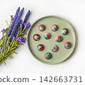 Collectible handmade tempered chocolate sweets with a glossy painted body on a round plate with blur elements. View from above 142663731
