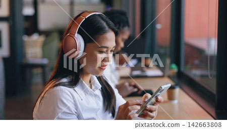 Woman, headphones and cafe with smartphone, streaming music and singing in shop, texting and social media. Happy, young and technology for podcast, listening and networking on subscription app Woman, headphones and cafe with smartphone, streaming music and singing in shop, texting and social media. Happy, young and technology for podcast, listening and networking on subscription app 142663808
