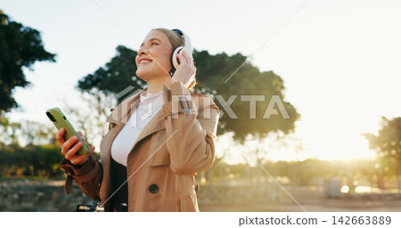 Woman, business and headphones with cellphone in park for work commute, streaming or podcast. Female person, walking and happiness in urban city for morning travel with music, entertainment or audio Woman, business and headphones with cellphone in park for work commute, streaming or podcast. Female person, walking and happiness in urban city for morning travel with music, entertainment or audio 142663889