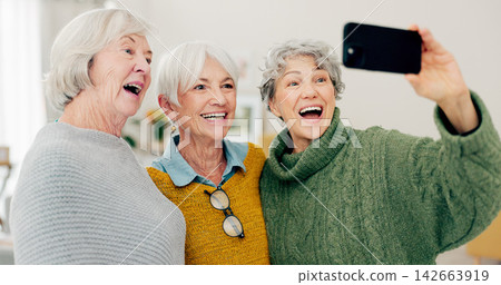 Selfie, fun and senior woman friends in a home for a visit during retirement together while looking happy. Social media, profile picture and smile with a group of elderly people bonding in a house Selfie, fun and senior woman friends in a home for a visit during retirement together while looking happy. Social media, profile picture and smile with a group of elderly people bonding in a house 142663919
