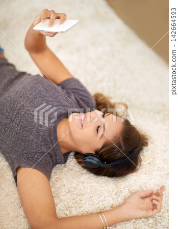 Headphones, smartphone and woman on carpet in home for audio playlist with streaming kpop music and radio. Mobile, listening and gen z girl on floor with podcast for learning language and chat app Headphones, smartphone and woman on carpet in home for audio playlist with streaming kpop music and radio. Mobile, listening and gen z girl on floor with podcast for learning language and chat app 142664593