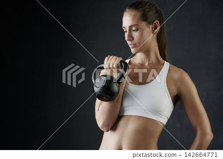 Fitness, sports and woman with kettle bell for strength training, weight lifting exercise isolated in studio. Female person or athlete and gym equipment for bodybuilder workout with dark background 142664771