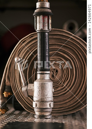Emergency, equipment and pipe with fire hose for security, danger or health and safety at station. Closeup of gear, tools or pressure extinguisher ready for rescue, service or firefighting operation Emergency, equipment and pipe with fire hose for security, danger or health and safety at station. Closeup of gear, tools or pressure extinguisher ready for rescue, service or firefighting operation 142664971