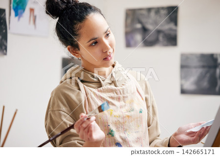 Thinking, woman and artist with paintbrush for art on canvas with passion or talent for design of masterpiece. Confident, painter and creative with inspiration or skill to create drawings for gallery Thinking, woman and artist with paintbrush for art on canvas with passion or talent for design of masterpiece. Confident, painter and creative with inspiration or skill to create drawings for gallery 142665171