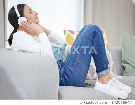 Headphones, music and woman on sofa in home for relaxing, resting and chill on weekend. Happy, smile and person on couch listening to audio, song and radio on streaming subscription in living room 142666643