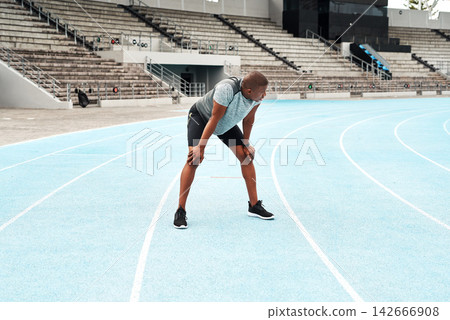 Black man, athlete and breathing after running on track for exercise, fitness and cardio in stadium. African male person, workout and runner on outdoor field for sports, health and wellness Black man, athlete and breathing after running on track for exercise, fitness and cardio in stadium. African male person, workout and runner on outdoor field for sports, health and wellness 142666908