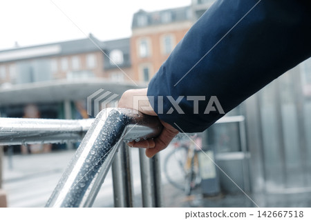 a man grips a rain-covered railing in Copenhagen a man grips a rain-covered railing in Copenhagen 142667518